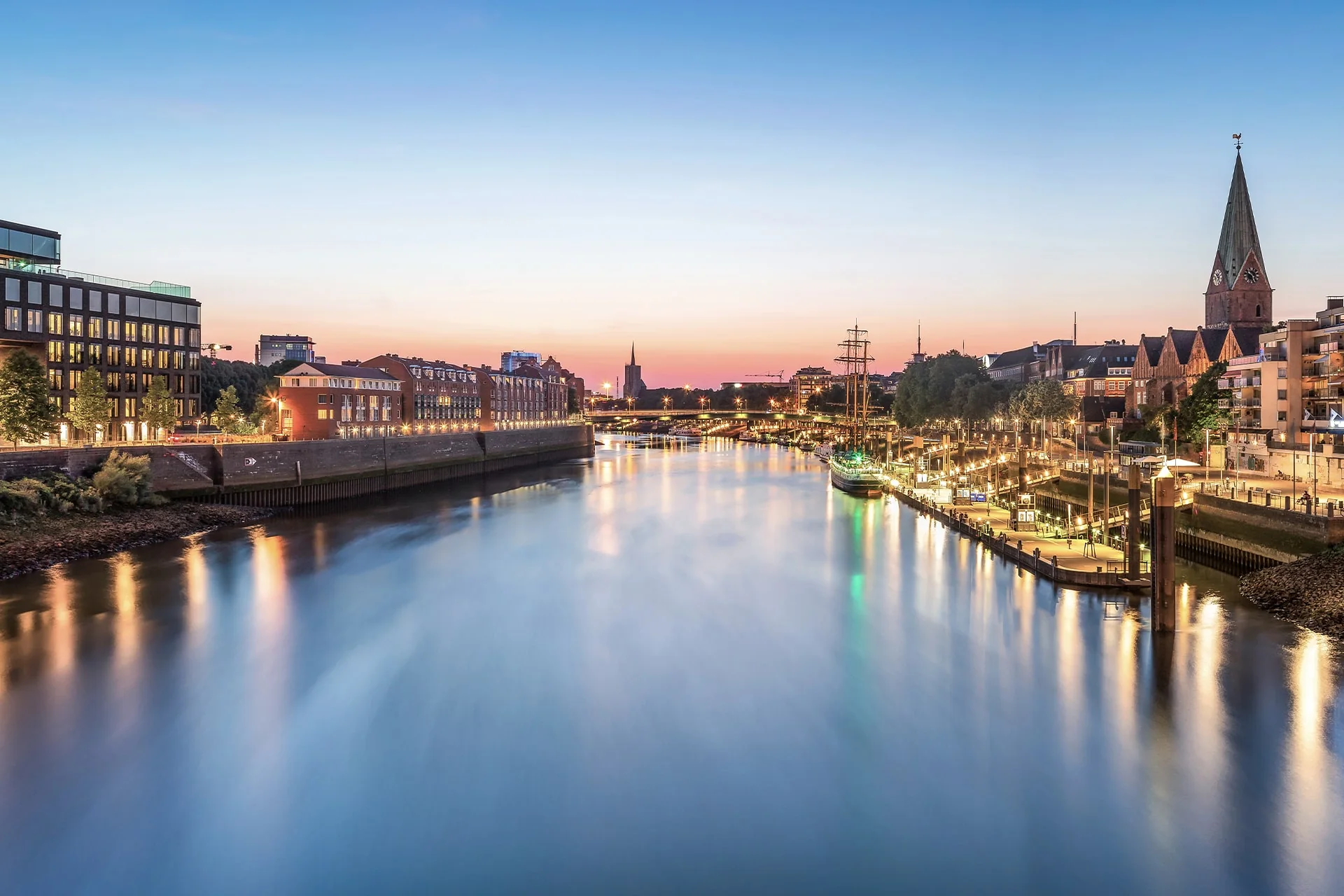 Blick über die Weser auf die Uferbebauung in Bremen bei Abendlicht